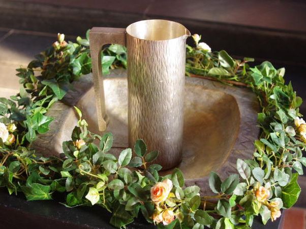 Mit Blumenkranz geschmücktes Taufbecken und Wasserkrug in der Martinskirche Cleverbrück